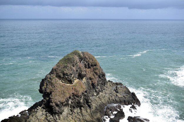 Foto foto di grande roccia con onde blu dell'oceano