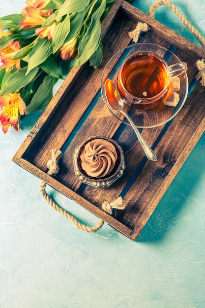 Photo of black tea in cup, cake with cream