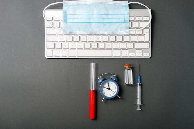 Photo of blood test vaccine and laptop, alarm clock