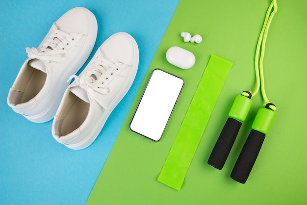 Photo of blue dumbbells and a blue exercise mat white sneakers and other sports equipment