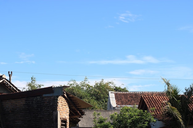 Photo of the blue sky above the roof tiles of the house