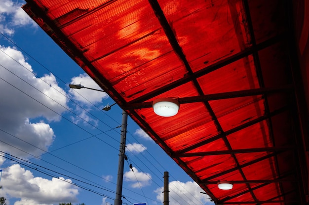 雲の青い空とランプの付いた波紋板で作られた天井の写真 夏のカフェの屋根