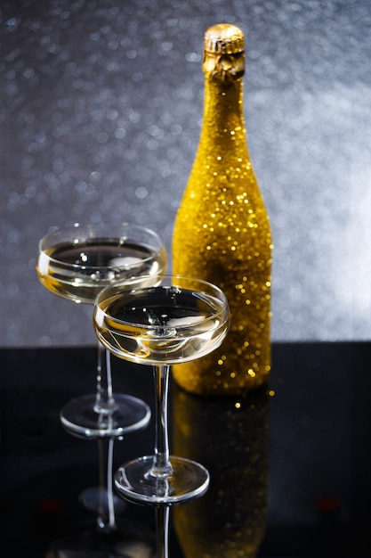 Photo of bottle of wine and two wine glasses on black table, gray background with spots