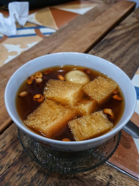 Photo of a bowl of Wedang Ronde a traditional Javanese dessert made of glutinous rice flour filled with peanut in ginger syrup