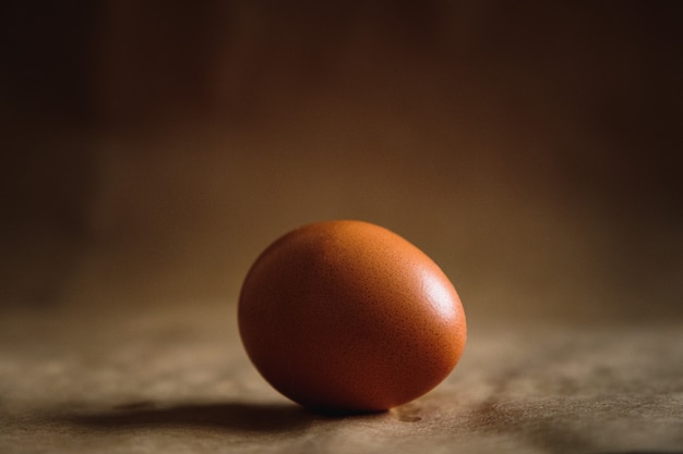 Photo of a brown chicken egg on a brown background.