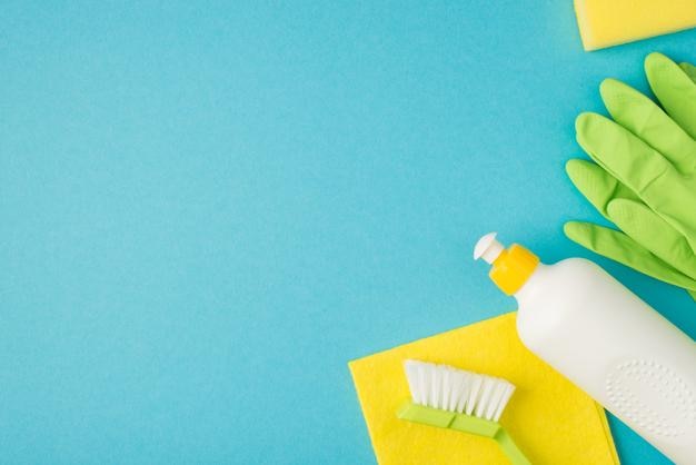 Above photo of brush cleaning rag soap and green gloves isolated on the blue background