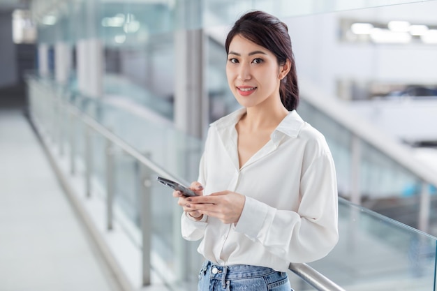 スマートフォンを探している写真ビジネス女性オープンスペースロフトオフィスパノラマウィンドウの背景