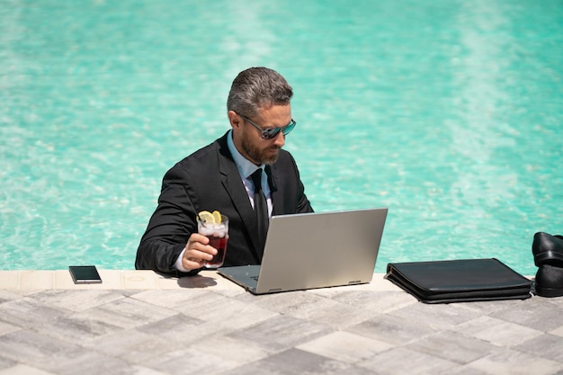 Photo of busy business man working remote in summer pool business man working remote online