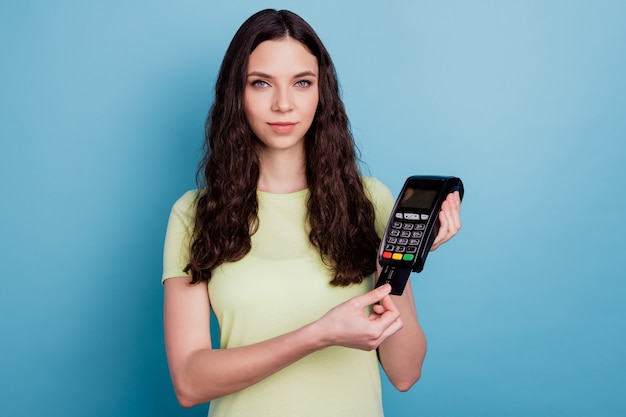 Photo of calm promoter lady paying credit card terminal look camera on blue background