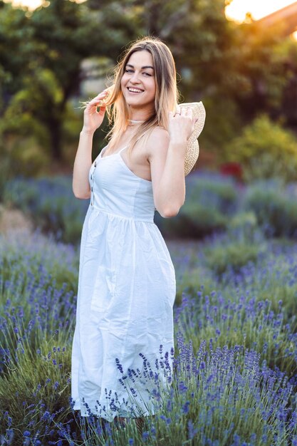 Photo of caucasian young woman in dress walking through lavender field