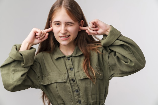 Foto foto di una giovane donna caucasica che si tappa le orecchie e guarda la telecamera