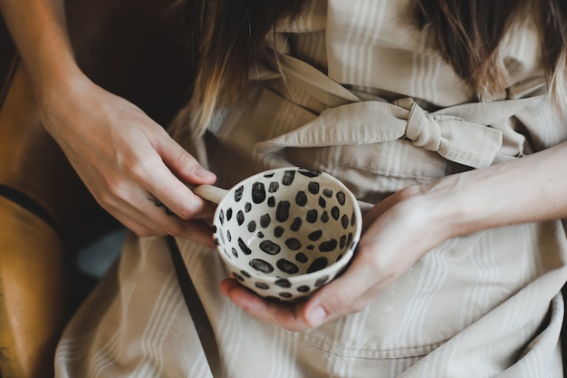 Photo of a ceramic cup in female hands closeup