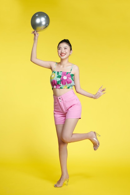 Photo of charming lady holding silver balloon wearing crop top isolated yellow color background