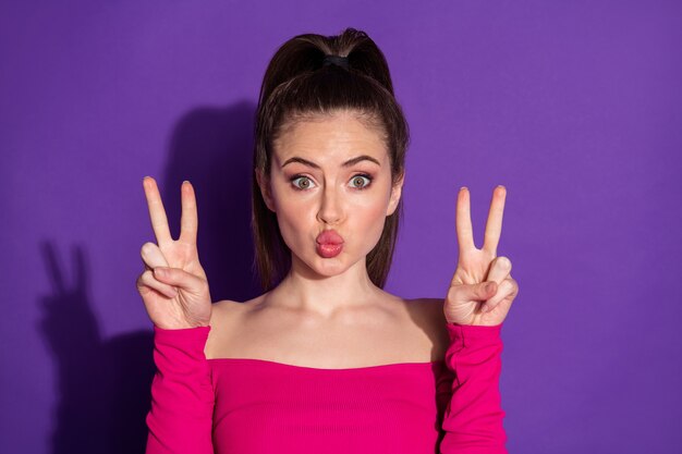 Photo of charming lovely sweet girl send air kiss make v-sign isolated over vivid color background