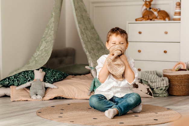 Photo of a charming young happy boy in a shirt playing at home.