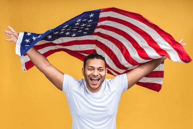 Photo of cheerful american african indian man protester raise\
american national flag black people revolution love all human\
beings express unity solidarity isolated over yellow\
background.