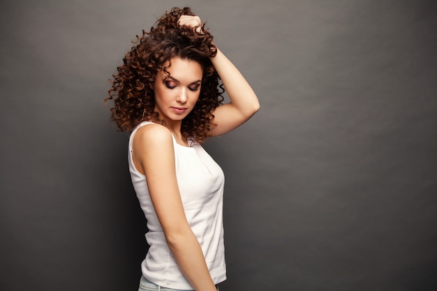 Photo of cheerful beautiful young woman standing isolated over gray wall