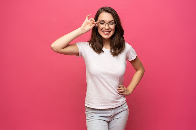 Photo of cheerful beautiful young woman standing isolated over pink wall background. Looking camera.