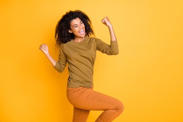 Photo photo of cheerful cute nice sweet pretty beautiful girl of black skin wearing orange pants trousers screaming shouting yes yeah isolated over vivid color background