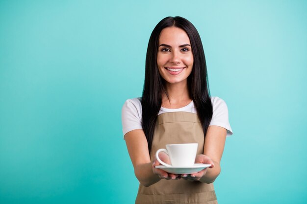 Photo of cheerful cute pretty charming woman server giving you cup of delicious coffee smiling toothily isolated teal color vibrant background