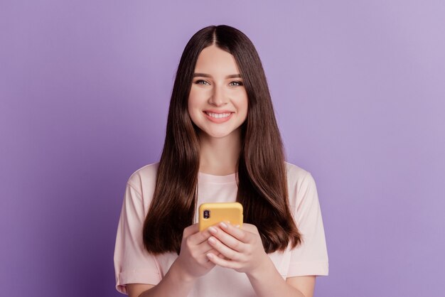 Photo of cheerful cute young woman hold mobile phone toothy beaming smile