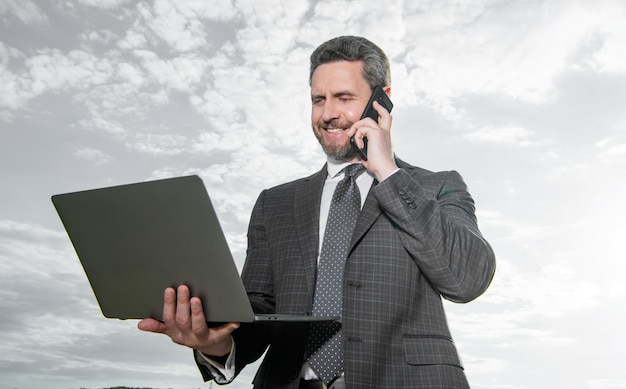 photo of cheerful freelancer man with laptop and phone freelancer man with laptop and phone on sky background freelancer man with laptop and phone outdoor freelancer man with laptop and phone