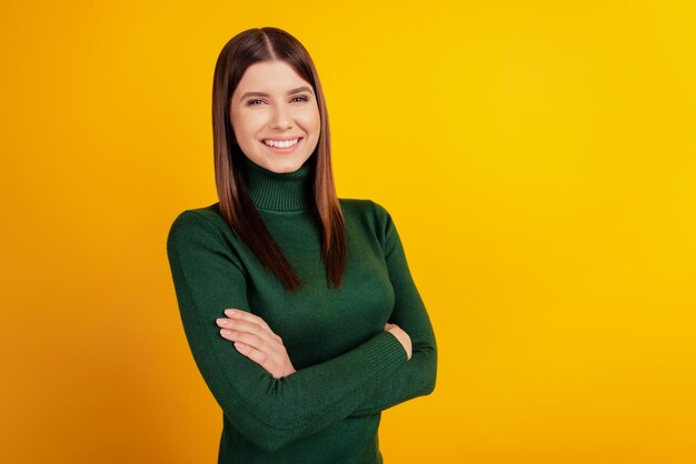 Foto di una donna allegra e orgogliosa, con le braccia incrociate, sorriso raggiante, indossa una maglietta verde isolata su sfondo giallo