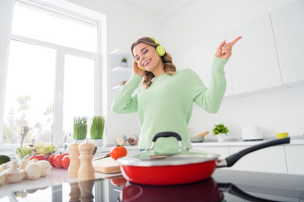 Photo of cheerful housewife cook listening headphones enjoy