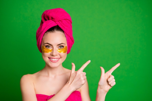 Photo of cheerful lady after shower use under eyes patches direct fingers empty space isolated green color background