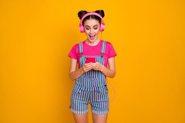 Photo of cheerful lady hold telephone listen music earphones on yellow background