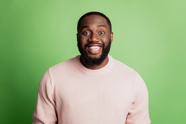 Photo of cheerful positive african man look camera toothy beaming smile wear white t-shirt over green background