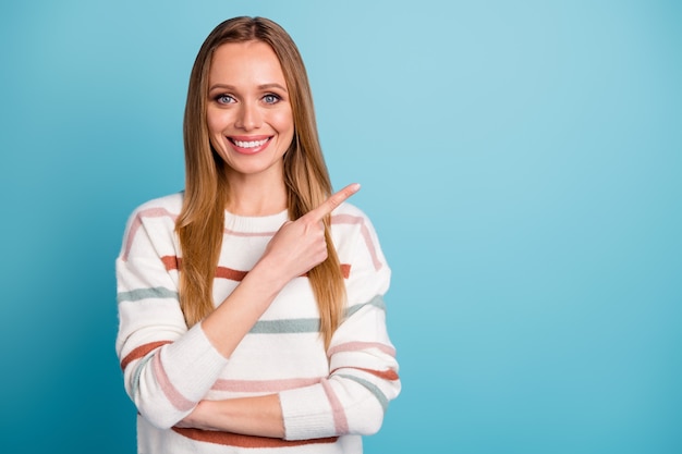 Photo of cheerful positive cute girl pointing into empty space for you to see important event information isolated blue pastel color wall