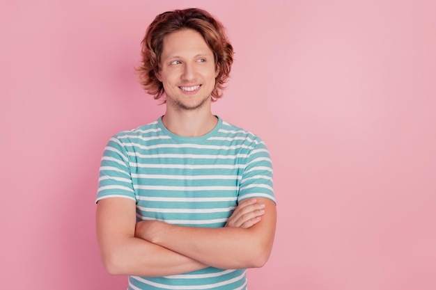 Фото веселого умного мужчины со скрещенными руками смотрят пустое пространство в повседневной синей полосатой футболке на розовом фоне
