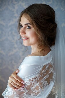 Ritratto del primo piano della foto di una sposa con trucco professionale, è in camice bianco, velo. giorno delle nozze della giovane donna. servizio fotografico, acconciatura, bellezza