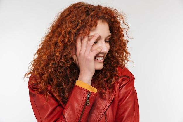 Photo closeup of alluring redhead woman 20s wearing leather jacket laughing and looking aside isolated over white wall