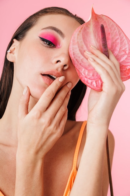 Photo closeup of brunette sexual woman posing with exotic flower