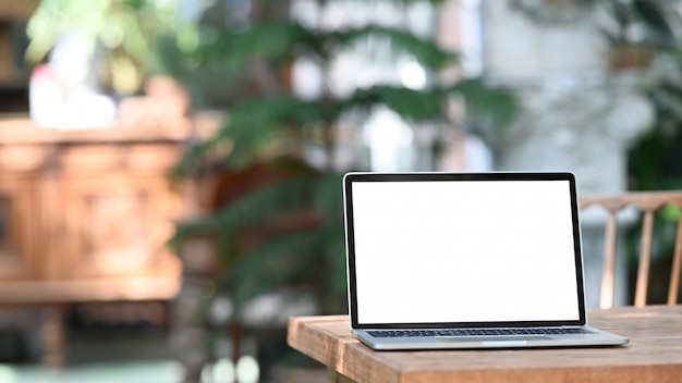 Photo of computer laptop with white blank screen putting outdoors on the modern table with classic cafe as 