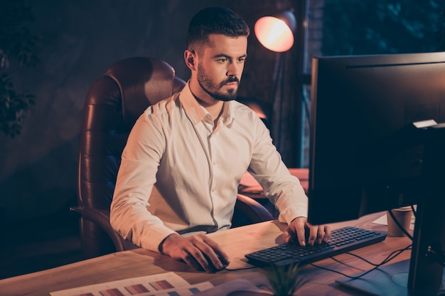 Photo of confident businessman working at night shift use computer