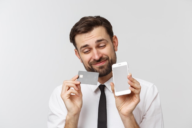 Photo of confident entrepreneur man in suit and tie holding smartphone and credit card for paying online