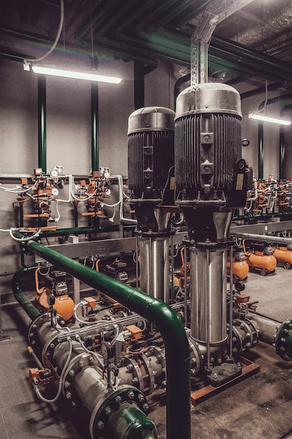 Photo contains film grain. water pump station and pipeline with\
tanks in an industrial room to supply high pressure water for\
firefight tasks. sprinkler pipes and control system to provide\
drink water