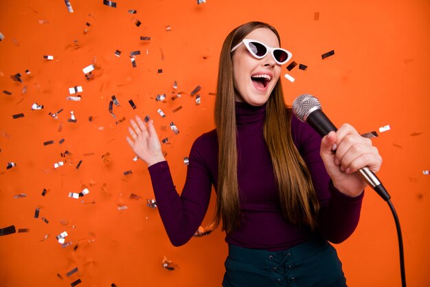 Photo of cool youth hipster girl enjoy karaoke party sing song mic wear violet purple jumper isolated over confetti fly fall bright shine color background