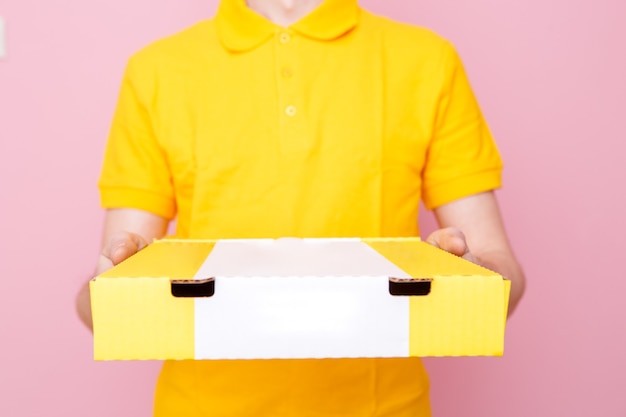 Photo of courier in yellow Tshirt with box with pizza on pink