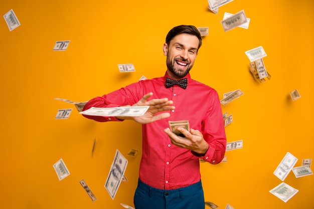 Photo of crazy funny guy hold fan of money bucks waste jackpot throw away banknotes money falling wear trendy red shirt bow tie clothes 