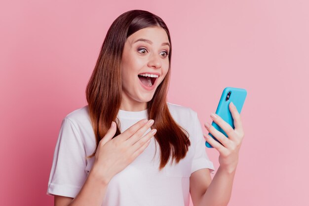 Foto di una ragazza pazza che usa il cellulare con la mano sul petto a bocca aperta guarda lo sguardo leggi il post