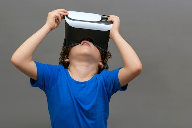 Photo of curlyhaired caucasian boy wearing virtual reality glasses