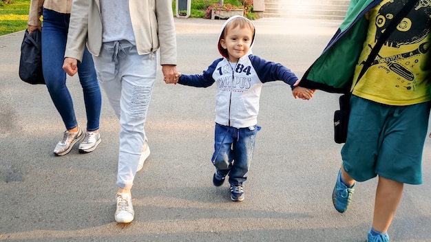 Photo of cute 3 years old toddler boy walking with his family in autumn park