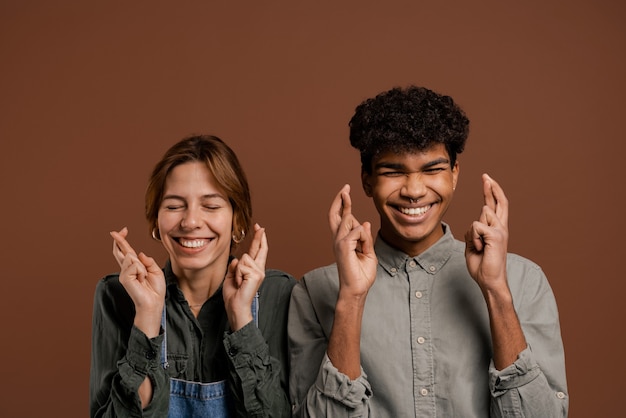 Photo of cute couple farmers cross their fingers to pray for something.