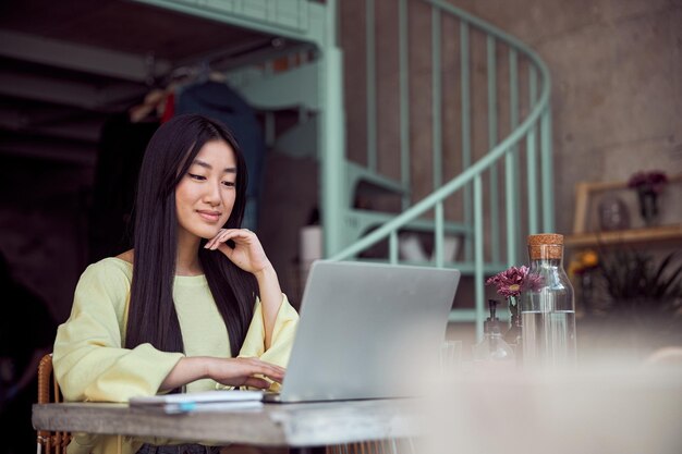 カフェでラップトップに取り組んでいるかわいい女性のフリーランサーの写真