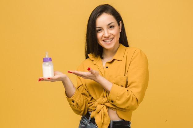 Photo of cute female holds baby bootle of milk