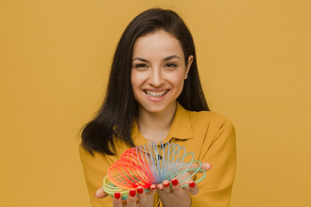 Photo of cute female with nice smile plays slinky